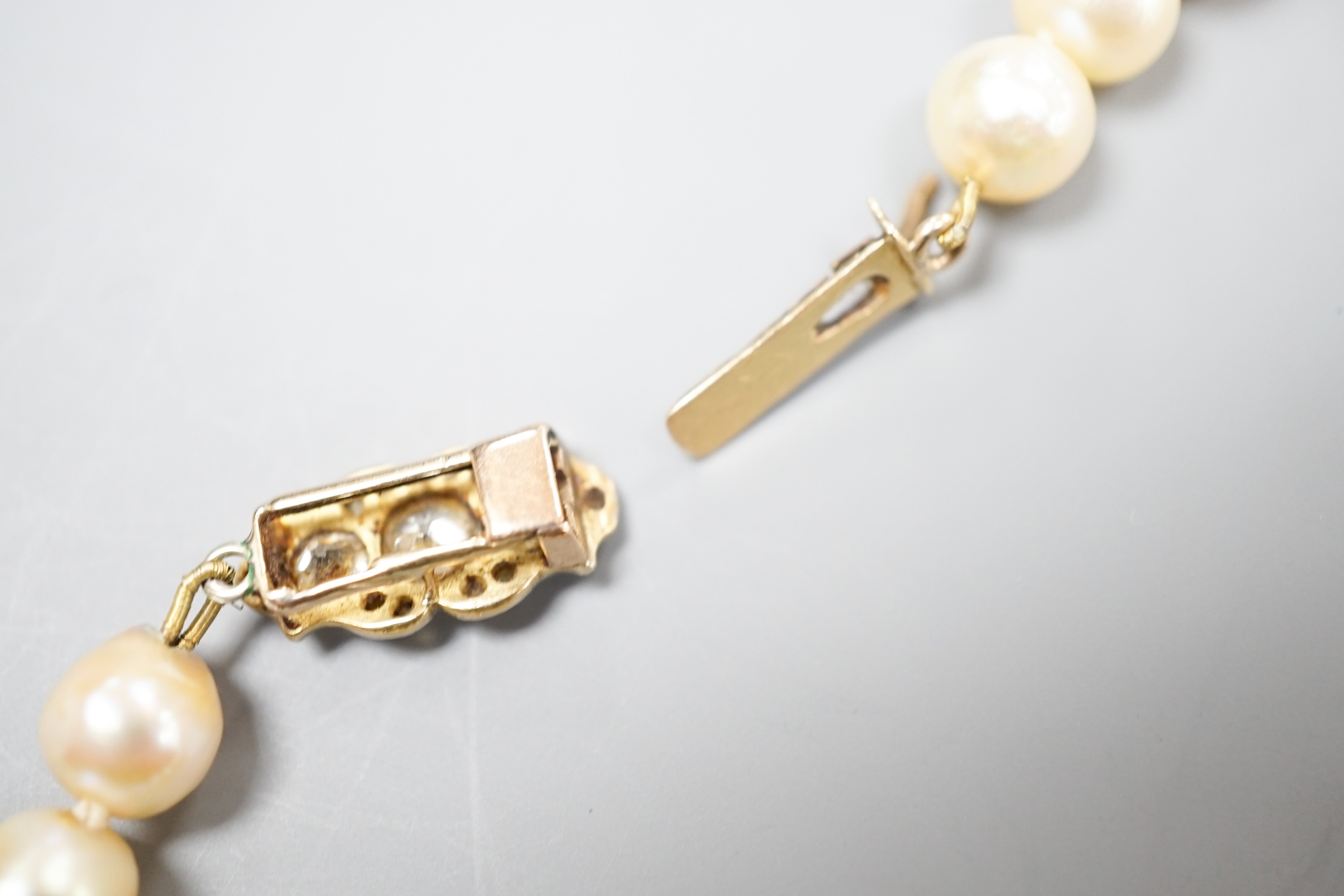 A single strand graduated pearl necklace (not tested for natural), with yellow metal and three stone diamond set clasp, 44cm.
